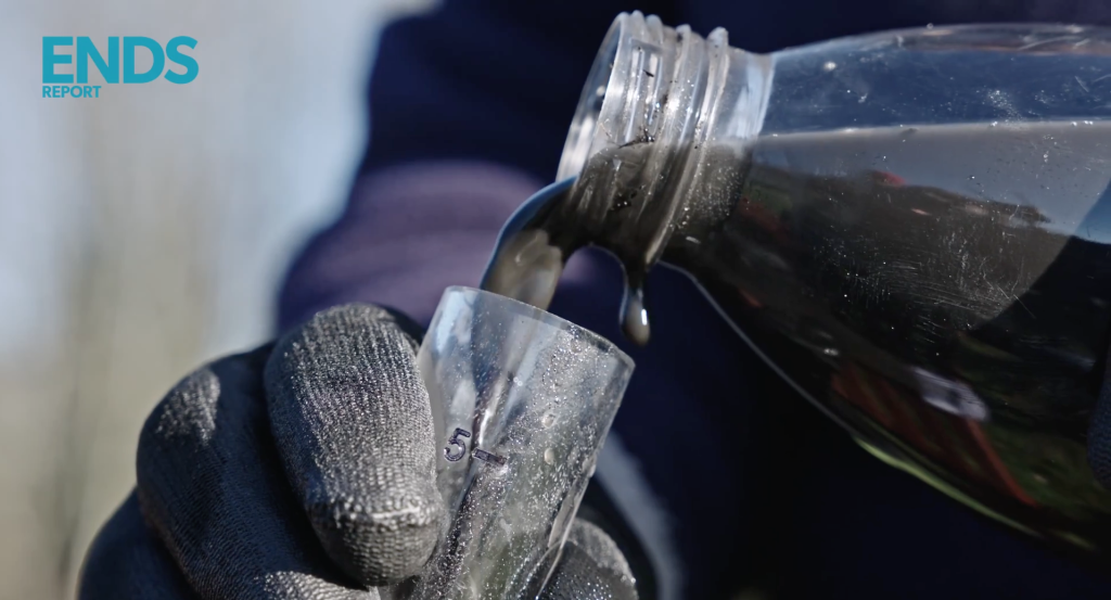 Pouring dark grey highway runoff into a tube